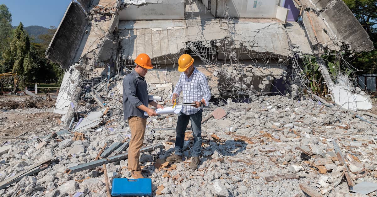 Construction workers stand in rubble of building collapse. | Maggiano, DiGirolamo & Lizzi